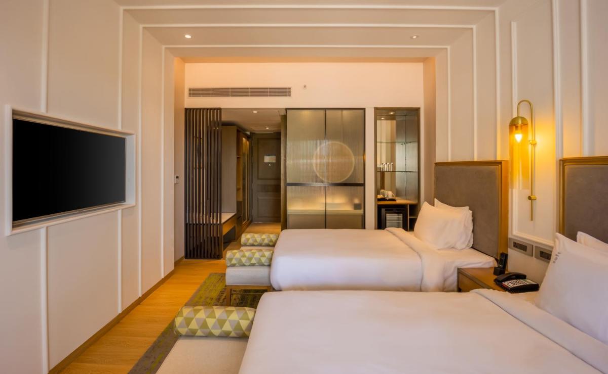 a hotel room with two beds and a flat screen tv at Holiday Inn Goa Candolim in Candolim a hotel room with two beds and a flat screen tv at Holiday Inn Goa Candolim in Candolim