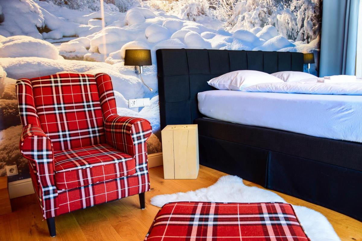 Schlafzimmer mit einem karierten Stuhl und einem Bett in der Unterkunft Design Hotel ALPENLIEBE - - - - Boutique-Flair - - - - in Inzell