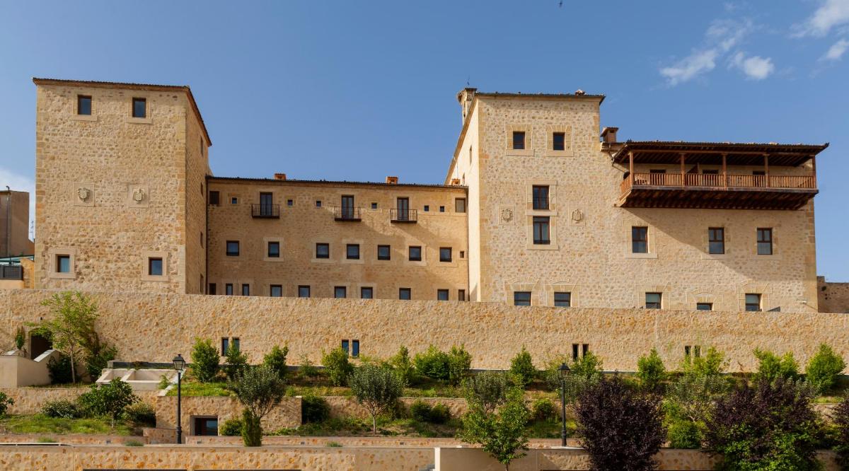 Dos grandes edificios de ladrillo detrás de un muro de piedra en Áurea Convento Capuchinos by Eurostars Hotel Company, en Segovia