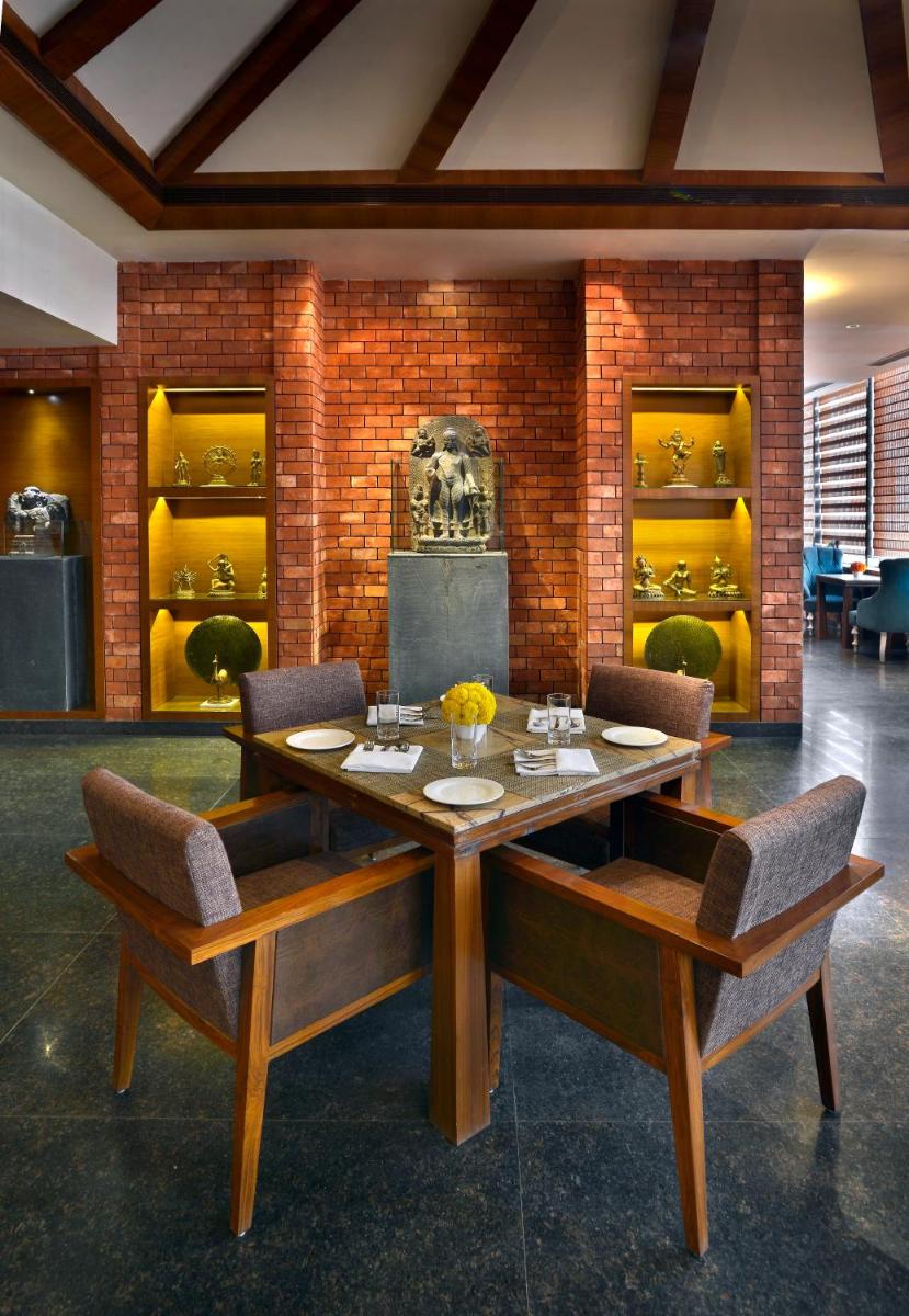 a dining room with a wooden table and chairs at The Lalit Great Eastern Kolkata in Kolkata a dining room with a wooden table and chairs at The Lalit Great Eastern Kolkata in Kolkata