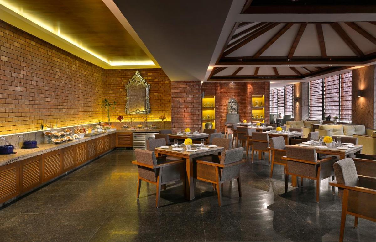 a restaurant with tables and chairs in a room at The Lalit Great Eastern Kolkata in Kolkata a restaurant with tables and chairs in a room at The Lalit Great Eastern Kolkata in Kolkata