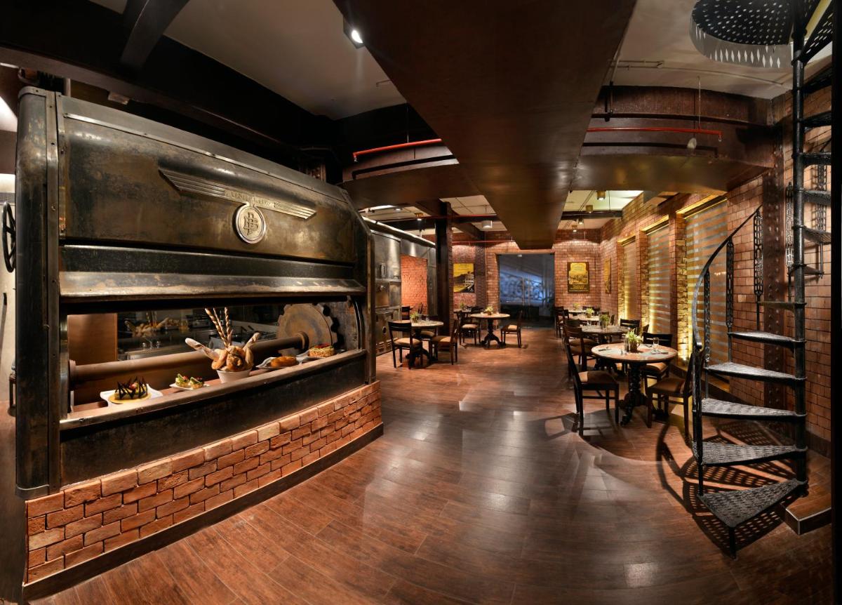 a restaurant with a large fireplace and tables and chairs at The Lalit Great Eastern Kolkata in Kolkata a restaurant with a large fireplace and tables and chairs at The Lalit Great Eastern Kolkata in Kolkata