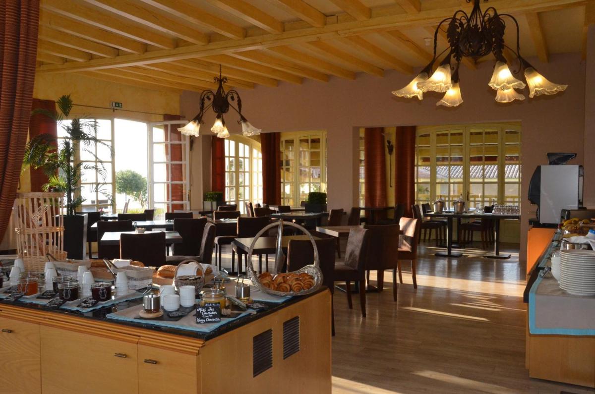 une salle à manger avec des tables et des chaises dans un restaurant dans l'établissement Hotel et Spa Les Cleunes Oléron, à Saint-Trojan-les-Bains