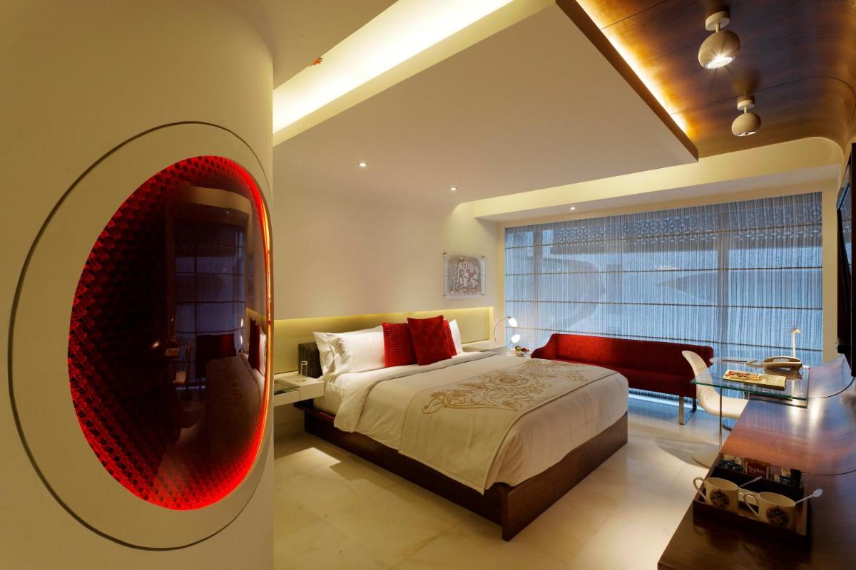 a bedroom with a large bed with a red oval mirror at The Park Hyderabad, Banjara Hills near Hussain Sagar Lake in Hyderabad a bedroom with a large bed with a red oval mirror at The Park Hyderabad, Banjara Hills near Hussain Sagar Lake in Hyderabad
