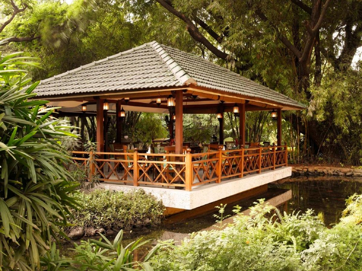 a gazebo in a garden next to a pond at The Oberoi Bengaluru in Bengaluru a gazebo in a garden next to a pond at The Oberoi Bengaluru in Bengaluru