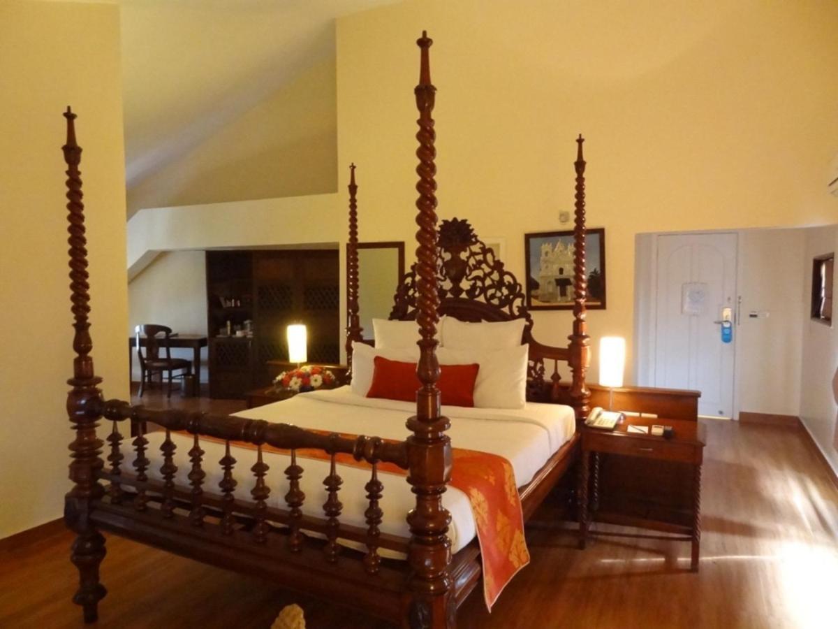 a bedroom with a large wooden bed in a room at The Crown Goa in Panaji