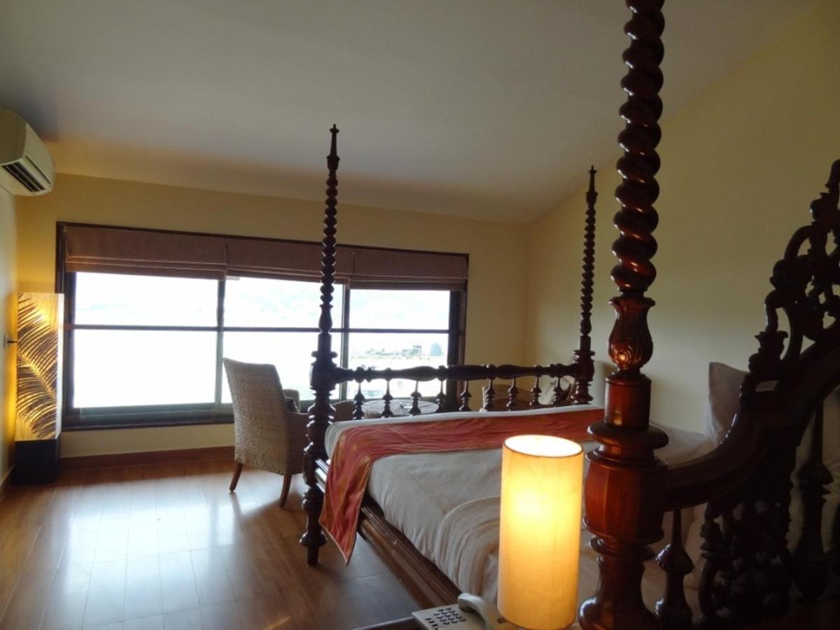 a bedroom with a canopy bed and a window at The Crown Goa in Panaji