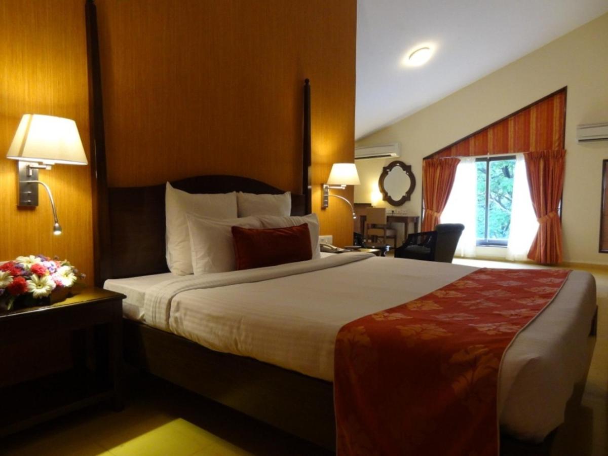a hotel room with a large bed and a window at The Crown Goa in Panaji
