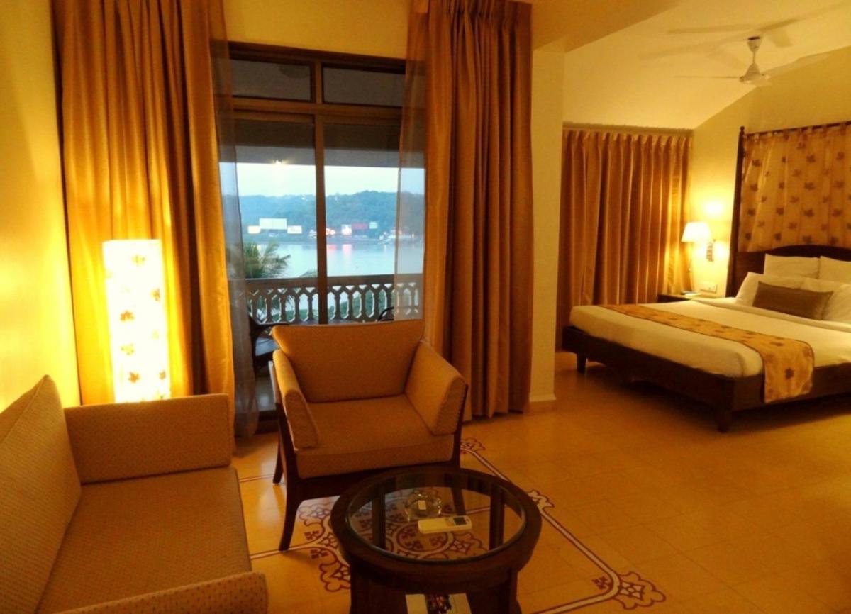 a hotel room with a bed and a balcony at The Crown Goa in Panaji