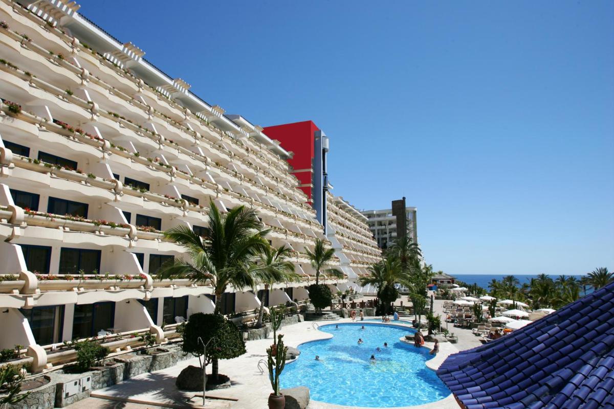 Un gran edificio con una piscina en frente. en Hotel LIVVO Lago Taurito & Aquapark, en Taurito