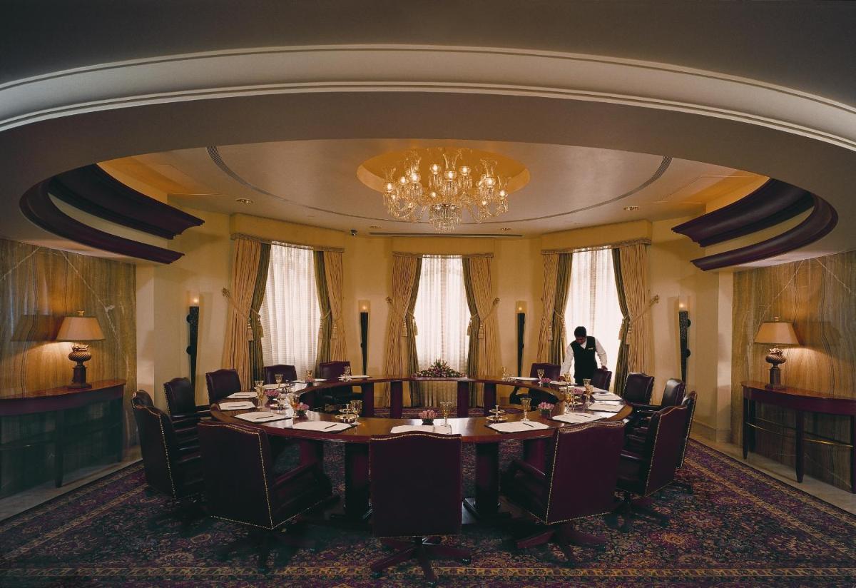 a meeting room with a large table and a man standing in the middle at The Leela Palace Bengaluru in Bengaluru a meeting room with a large table and a man standing in the middle at The Leela Palace Bengaluru in Bengaluru