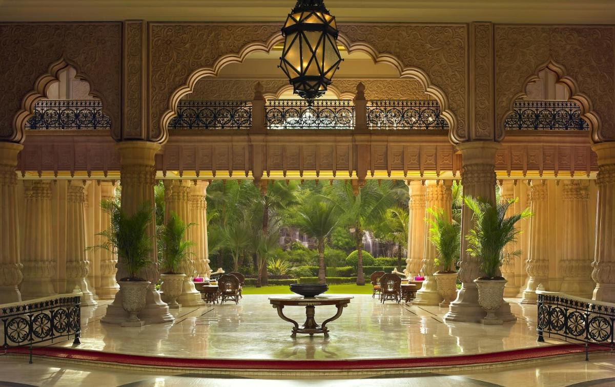 a large lobby with a table in the middle of a building at The Leela Palace Bengaluru in Bengaluru a large lobby with a table in the middle of a building at The Leela Palace Bengaluru in Bengaluru