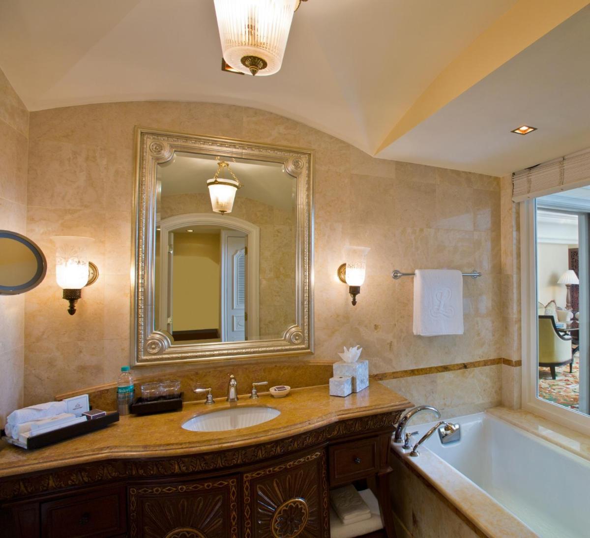 a bathroom with a sink and a tub and a mirror at The Leela Palace Bengaluru in Bengaluru a bathroom with a sink and a tub and a mirror at The Leela Palace Bengaluru in Bengaluru