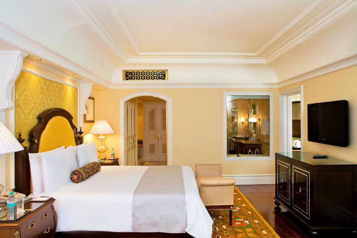a bedroom with a large white bed and a flat screen tv at The Leela Palace Bengaluru in Bengaluru a bedroom with a large white bed and a flat screen tv at The Leela Palace Bengaluru in Bengaluru
