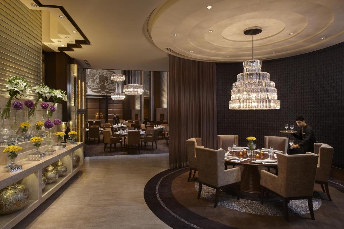 a dining room with a table and chandeliers at The Leela Palace New Delhi in New Delhi a dining room with a table and chandeliers at The Leela Palace New Delhi in New Delhi
