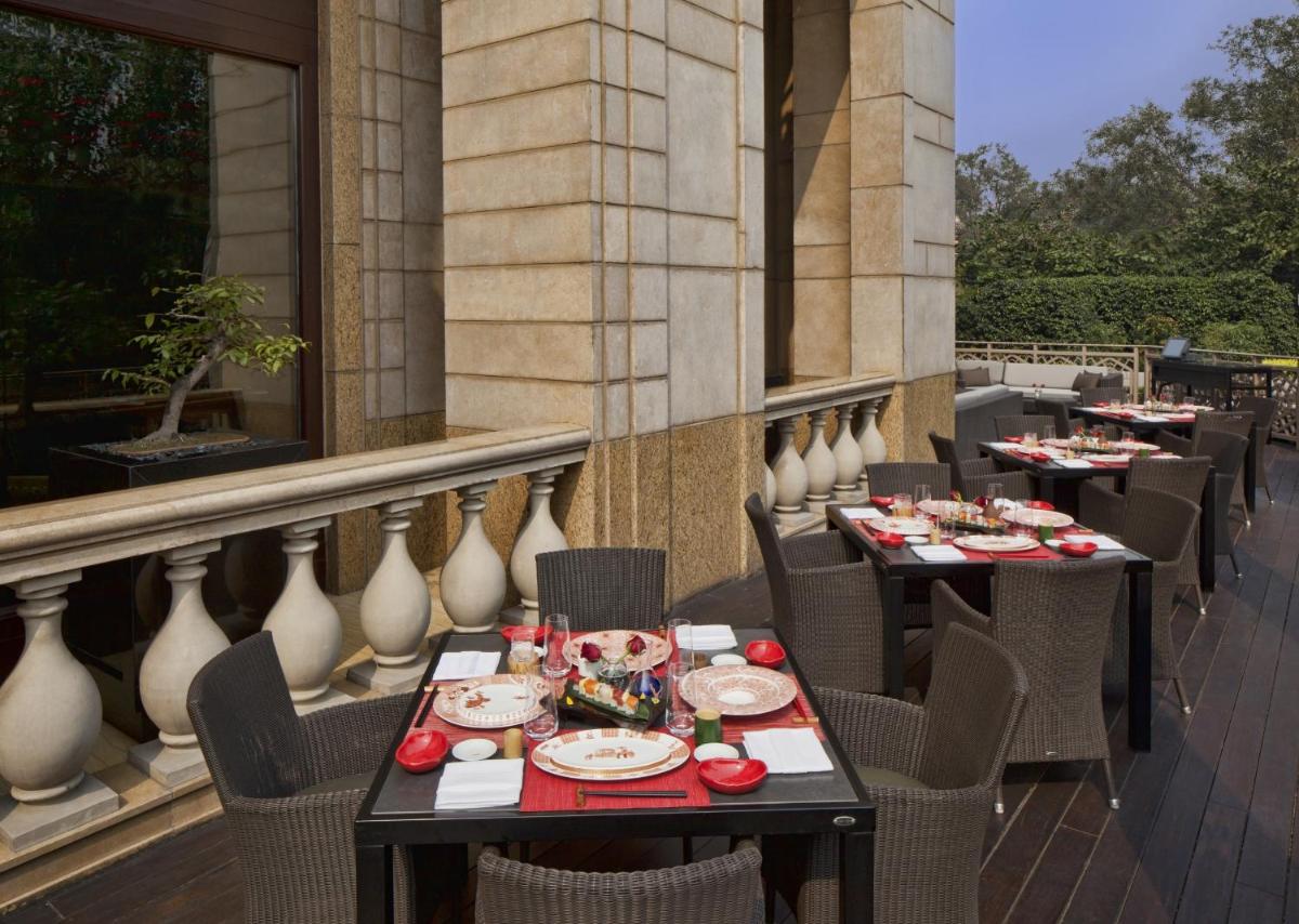 a restaurant with tables and chairs on a balcony at The Leela Palace New Delhi in New Delhi a restaurant with tables and chairs on a balcony at The Leela Palace New Delhi in New Delhi