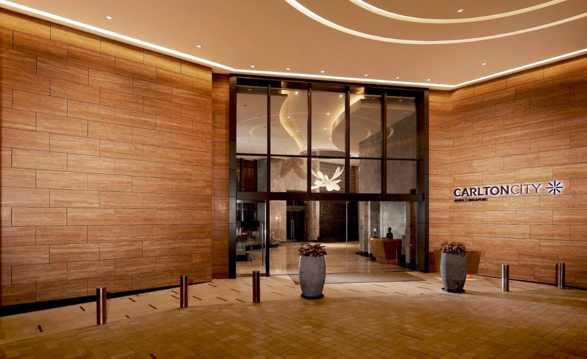 a lobby of a building with two vases at Carlton City Hotel Singapore in Singapore