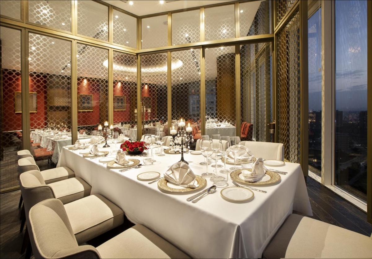 a dining room with a long white table and chairs at The Leela Bhartiya City Bengaluru in Bengaluru a dining room with a long white table and chairs at The Leela Bhartiya City Bengaluru in Bengaluru