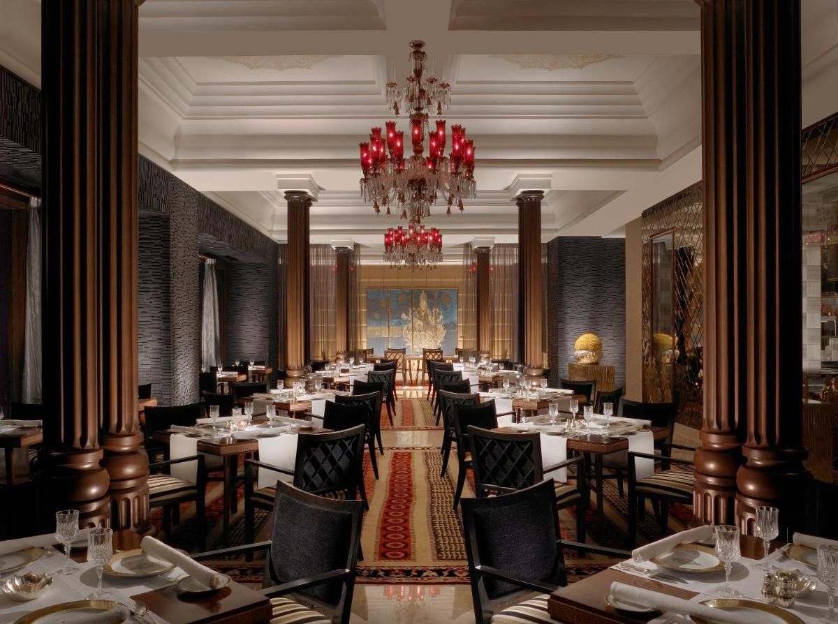 a dining room with tables and chairs and a chandelier at The Leela Palace Chennai in Chennai a dining room with tables and chairs and a chandelier at The Leela Palace Chennai in Chennai