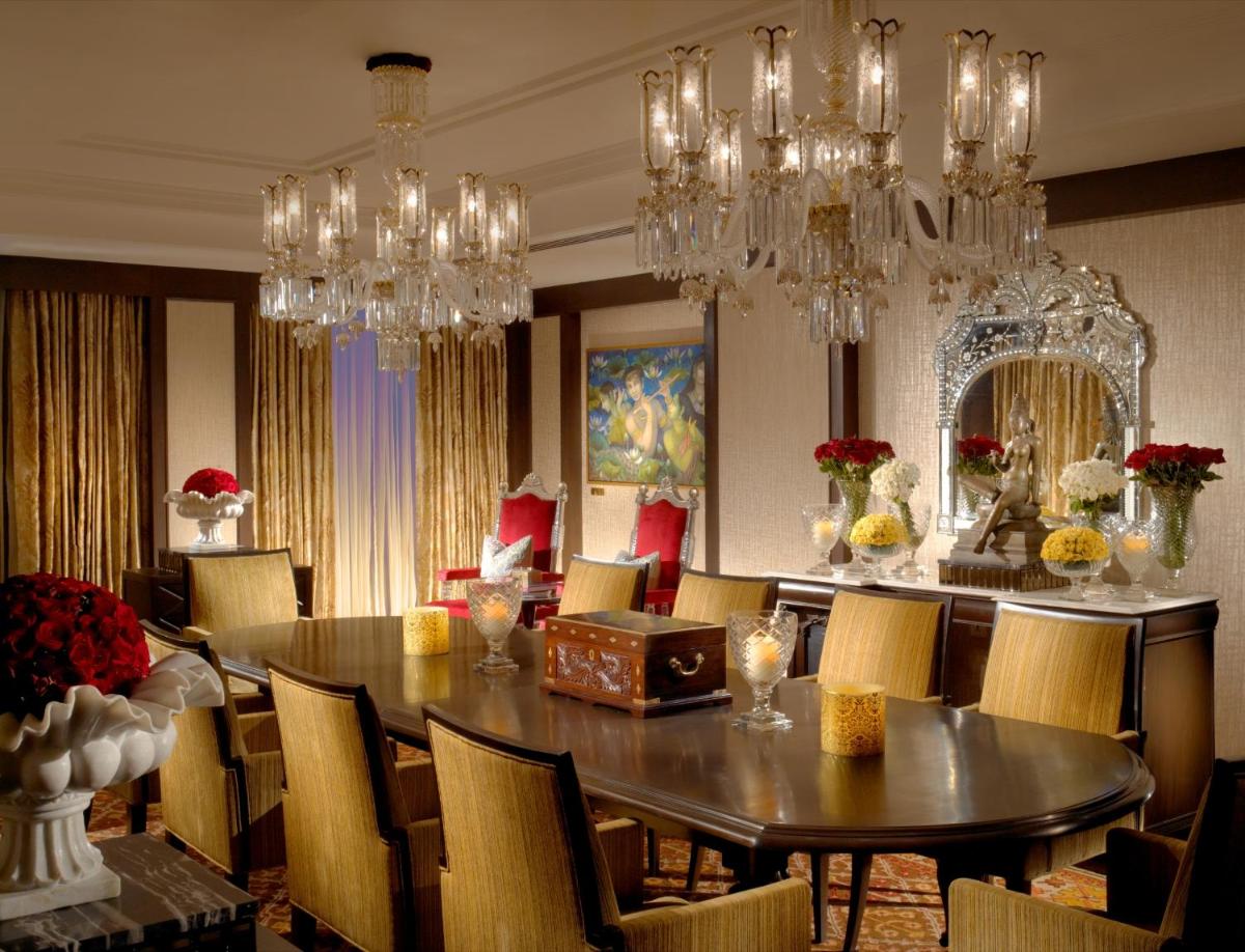 a dining room with a table and chairs and chandeliers at The Leela Palace Chennai in Chennai a dining room with a table and chairs and chandeliers at The Leela Palace Chennai in Chennai