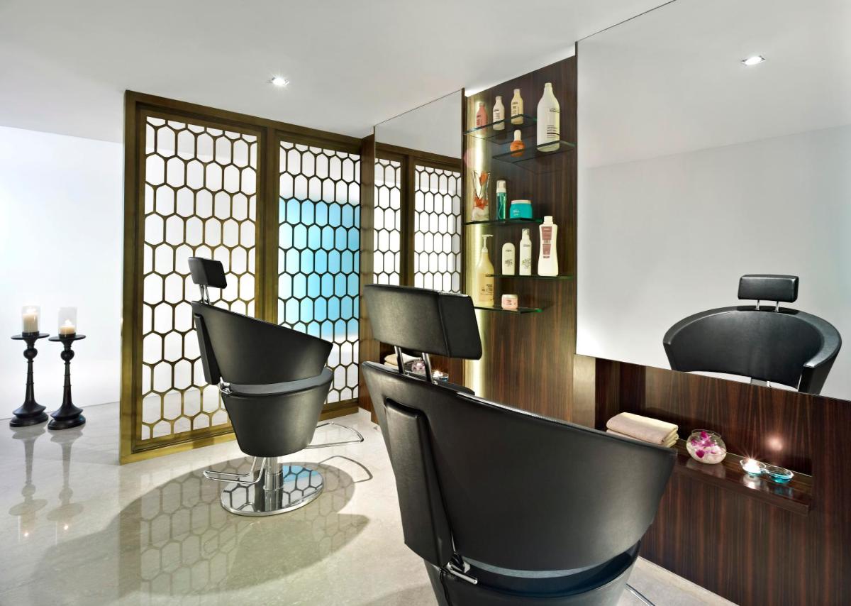 a hair salon with black chairs and a mirror at Vivanta Chennai IT Expressway OMR in Chennai