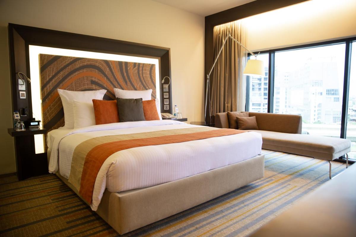 a hotel room with a large bed and a couch at Novotel Kolkata Hotel and Residences in Kolkata a hotel room with a large bed and a couch at Novotel Kolkata Hotel and Residences in Kolkata