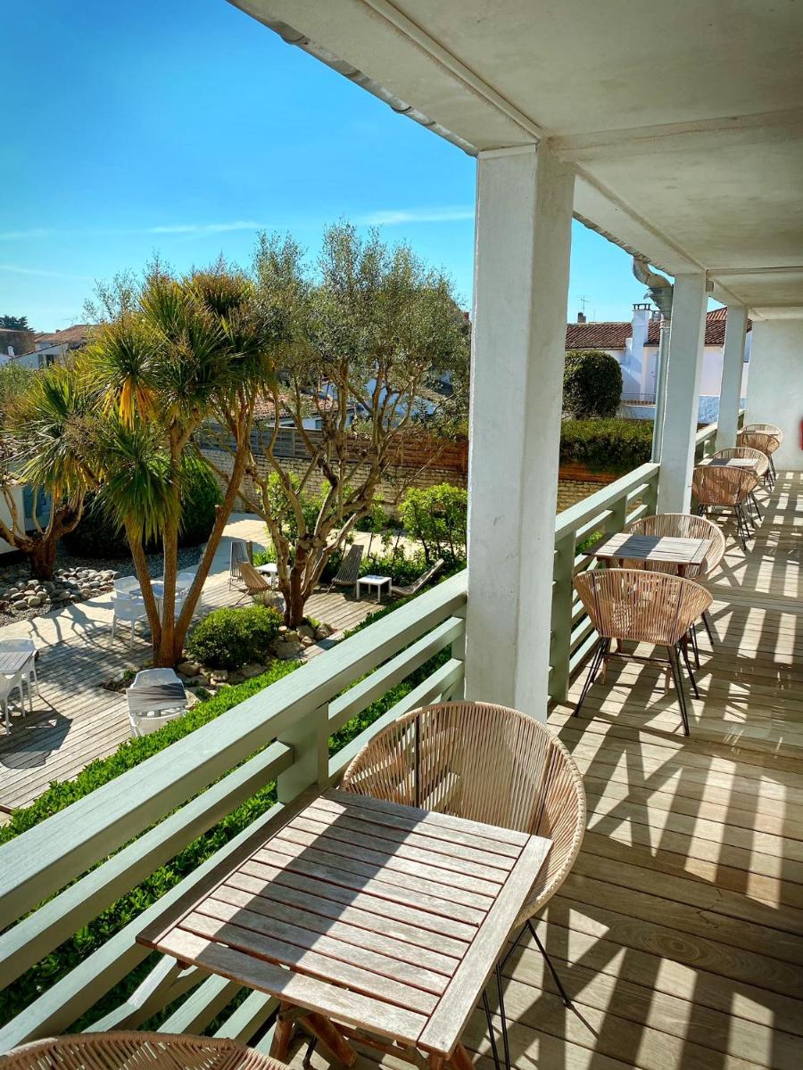 une véranda avec des chaises, une table et des arbres dans l'établissement Hotel L'Océan, au Bois-Plage-en-Ré