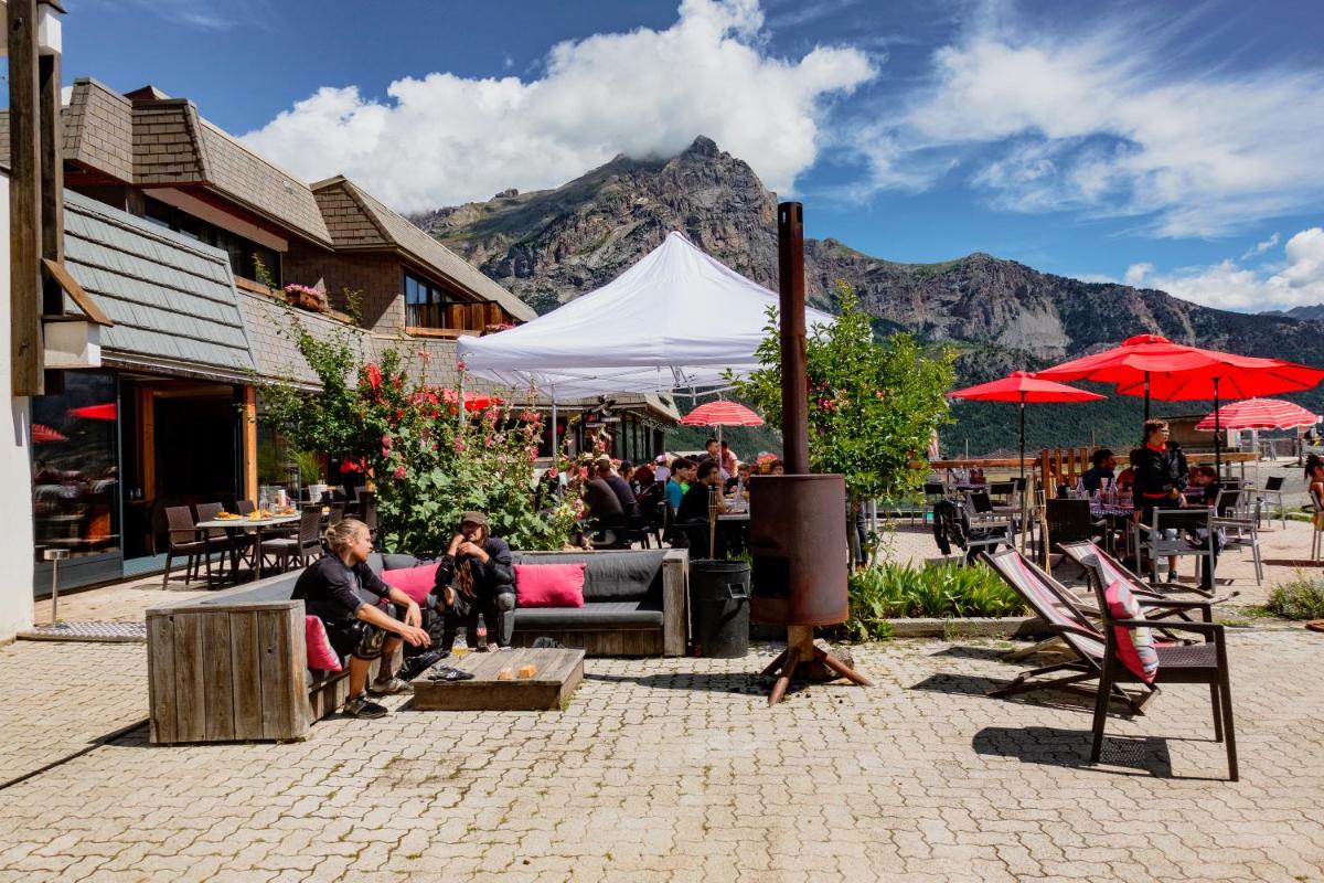 un groupe de personnes assises sous des parasols sur une terrasse dans l'établissement Hôtel Restaurant Saint Roch, à Puy-Saint-Vincent