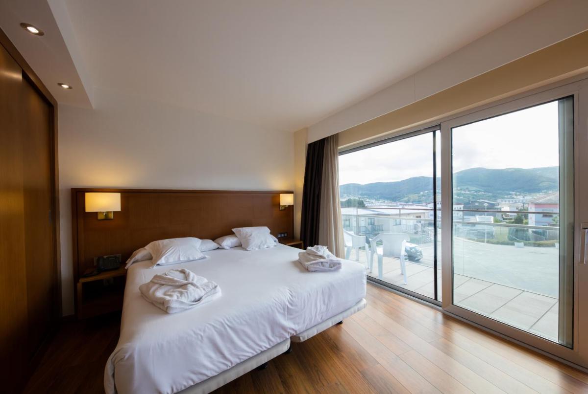 1 dormitorio con 1 cama con sábanas blancas y ventana grande en Hotel Thalasso Cantabrico Las Sirenas 4 Superior, en Viveiro