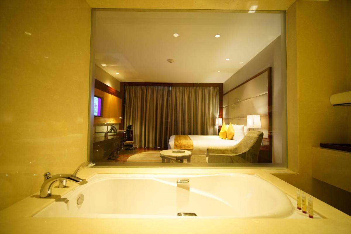 a bathroom with a tub and a bedroom with a bed at Crowne Plaza Kochi by IHG in Cochin