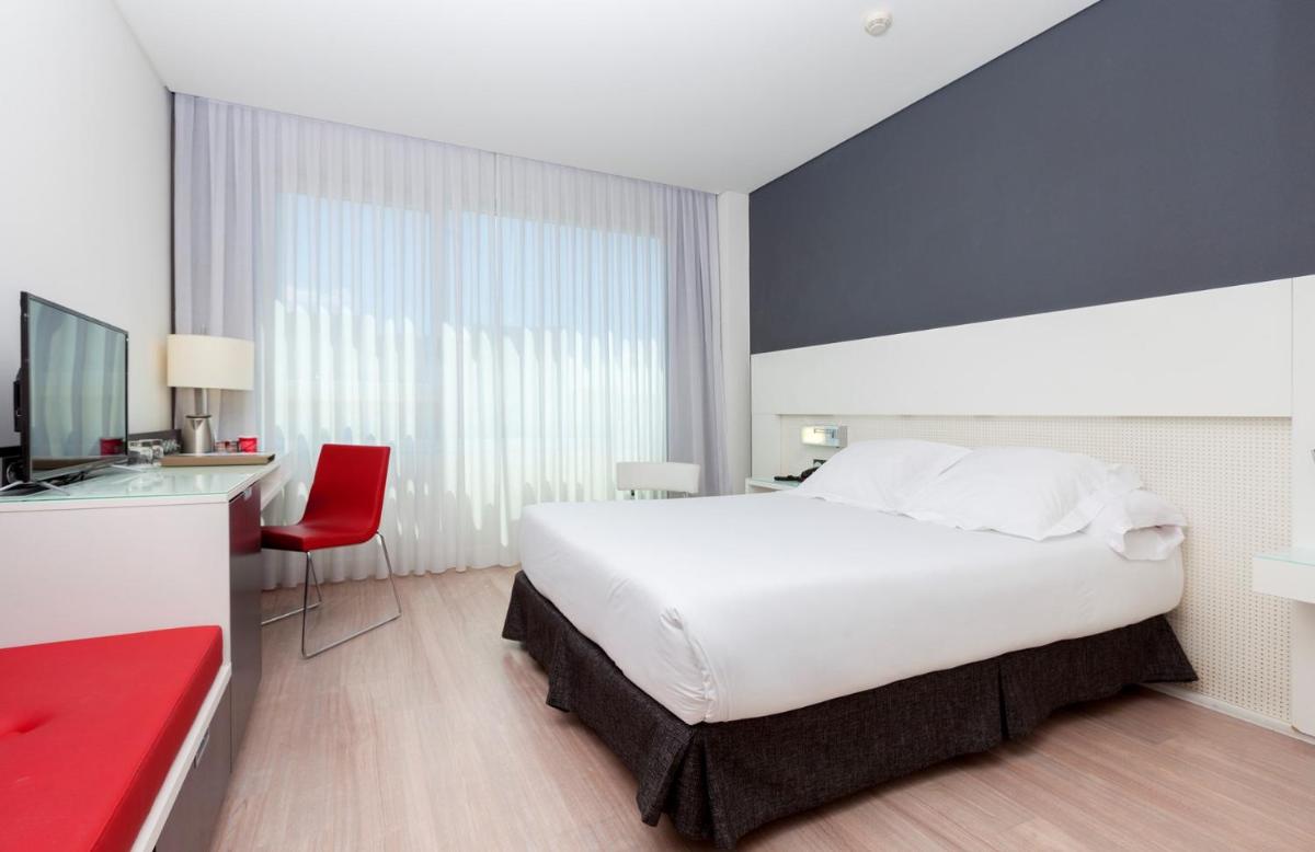 Un dormitorio con una gran cama blanca y un escritorio. en Axor Feria, en Madrid