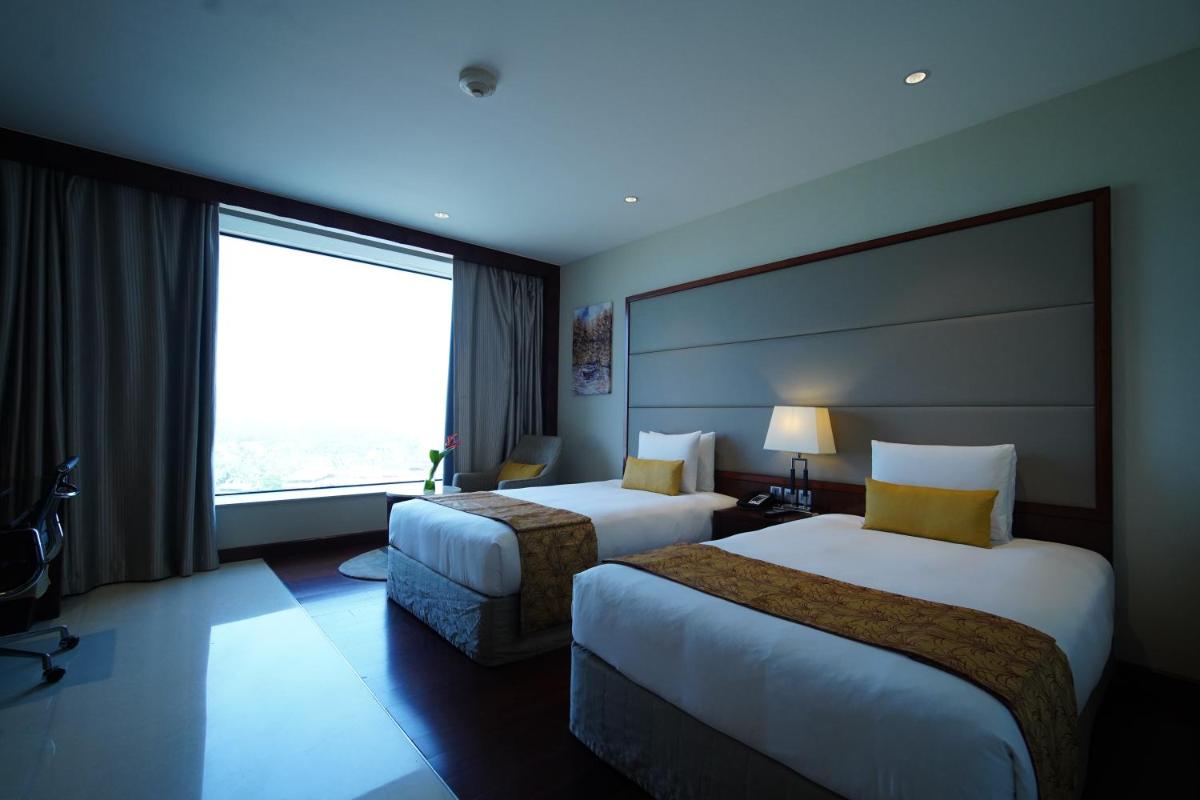 a hotel room with two beds and a large window at Crowne Plaza Kochi by IHG in Cochin
