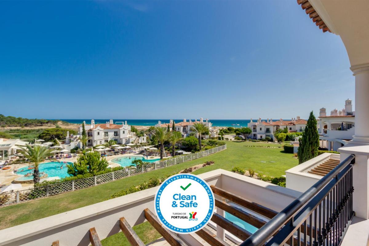 uma vista para a piscina e para o oceano a partir da varanda de um resort em Dunas Douradas Beach Club no Vale do Lobo