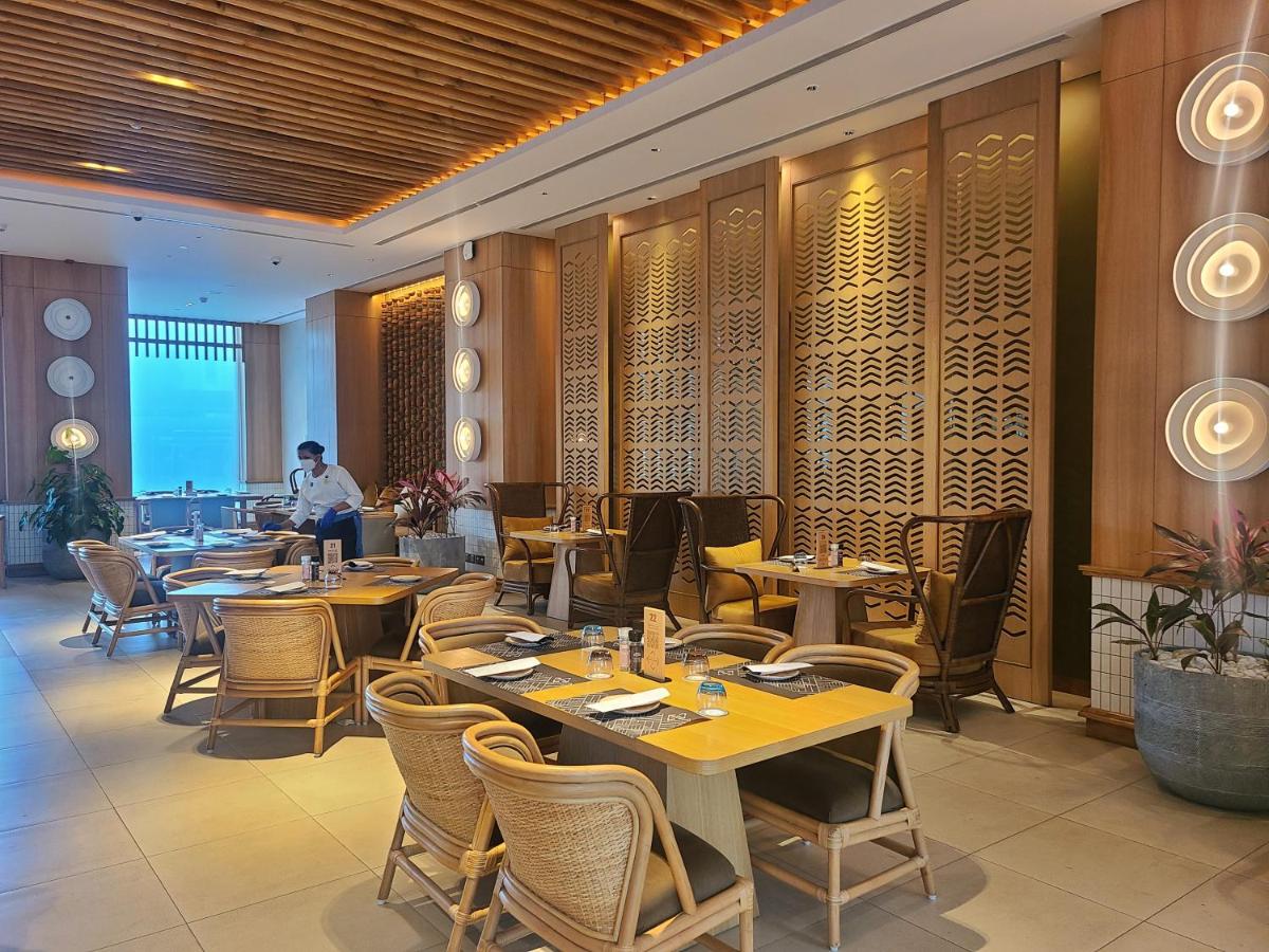 a restaurant with tables and chairs and a man in the background at Novotel Hyderabad Airport in Hyderabad