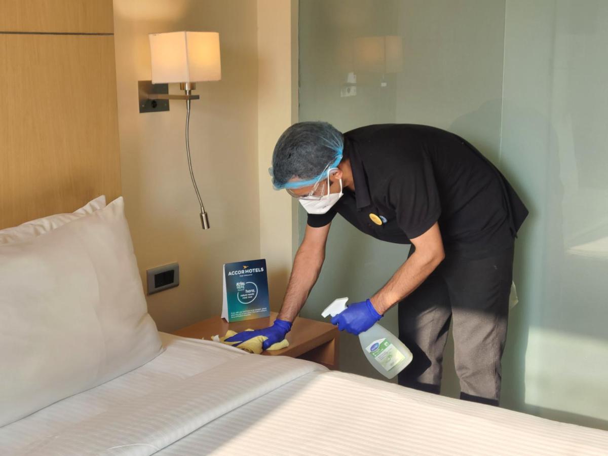 a man in a hotel room making a bed at Novotel Hyderabad Airport in Hyderabad