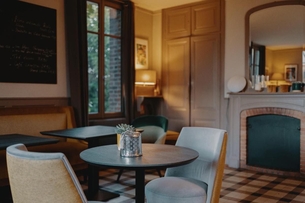 un restaurant avec deux tables et des chaises ainsi qu'une cheminée dans l'établissement La Fraîchette-Hôtel & Spa, à Honfleur