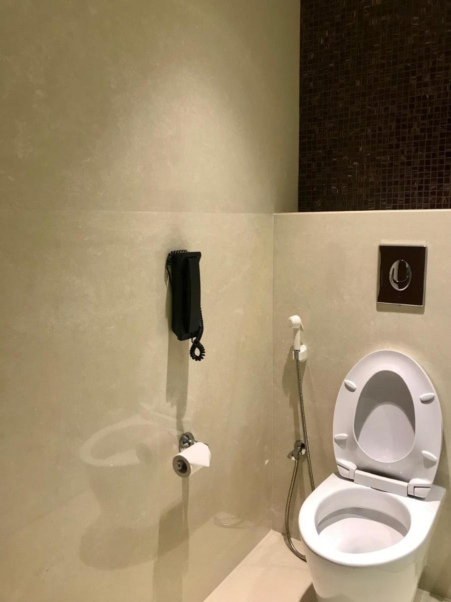 a bathroom with a toilet and a phone on the wall at Crowne Plaza Kochi by IHG in Cochin