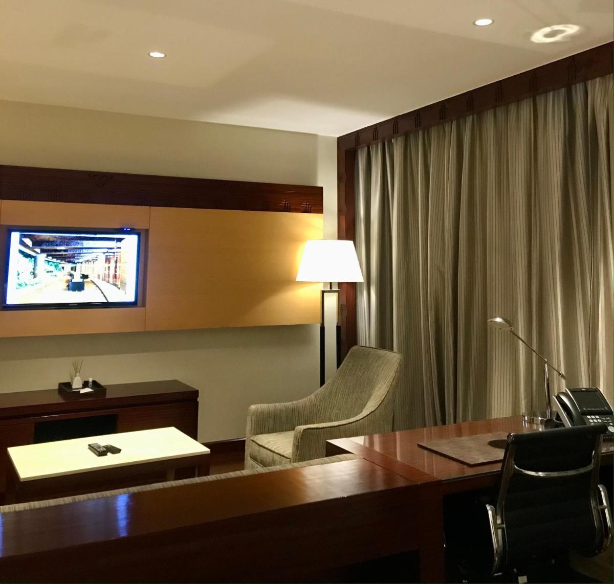 a hotel room with a desk and a television on the wall at Crowne Plaza Kochi by IHG in Cochin