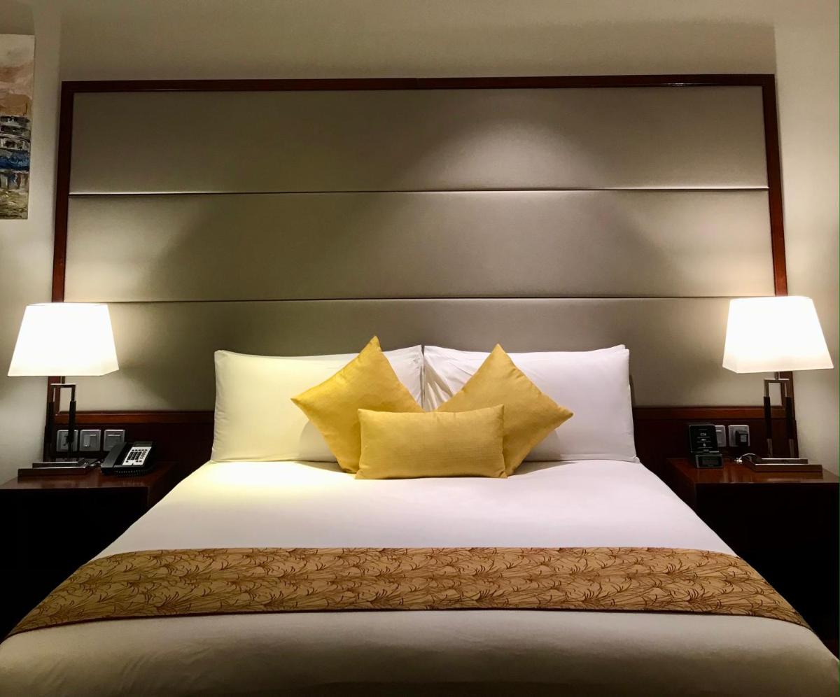 a bedroom with a large white bed with yellow pillows at Crowne Plaza Kochi by IHG in Cochin