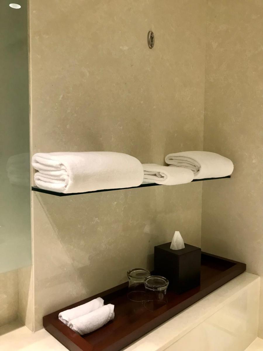 a mirror with two towels on a shelf in a bathroom at Crowne Plaza Kochi by IHG in Cochin
