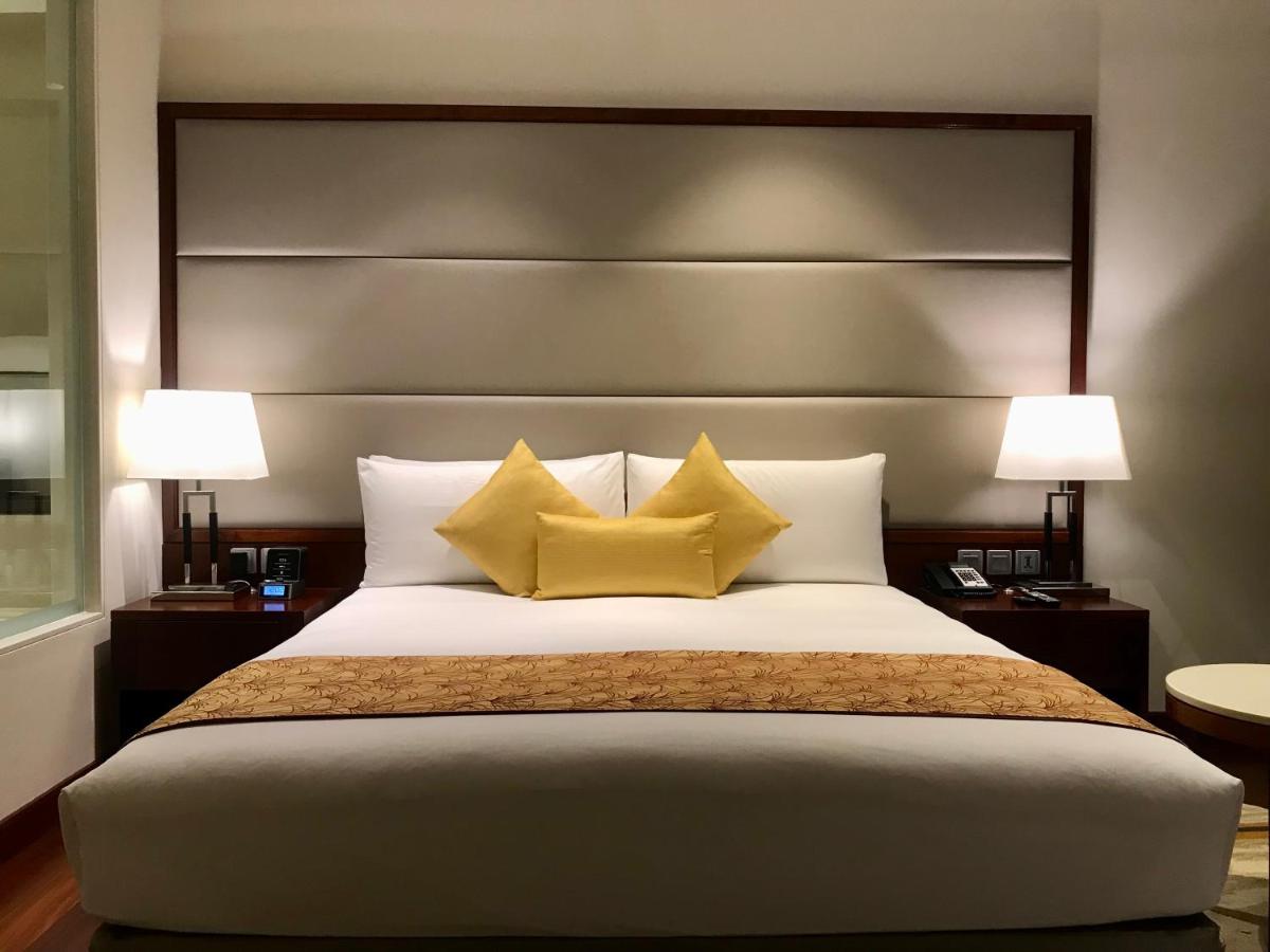 a bedroom with a large bed with two yellow pillows at Crowne Plaza Kochi by IHG in Cochin