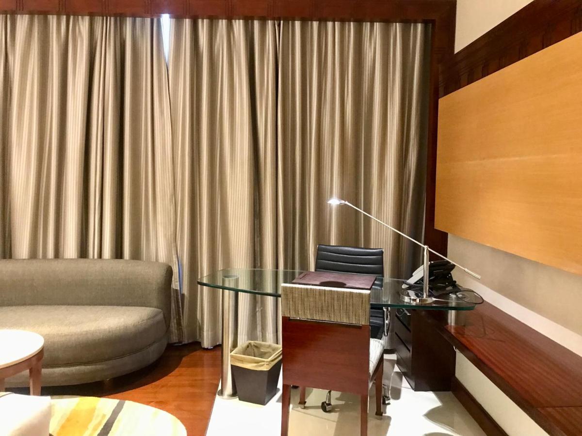a living room with a glass table and a couch at Crowne Plaza Kochi by IHG in Cochin