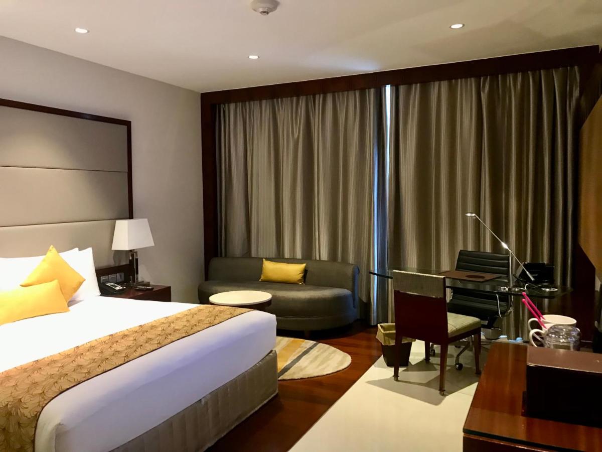 a hotel room with a bed and a couch and a desk at Crowne Plaza Kochi by IHG in Cochin