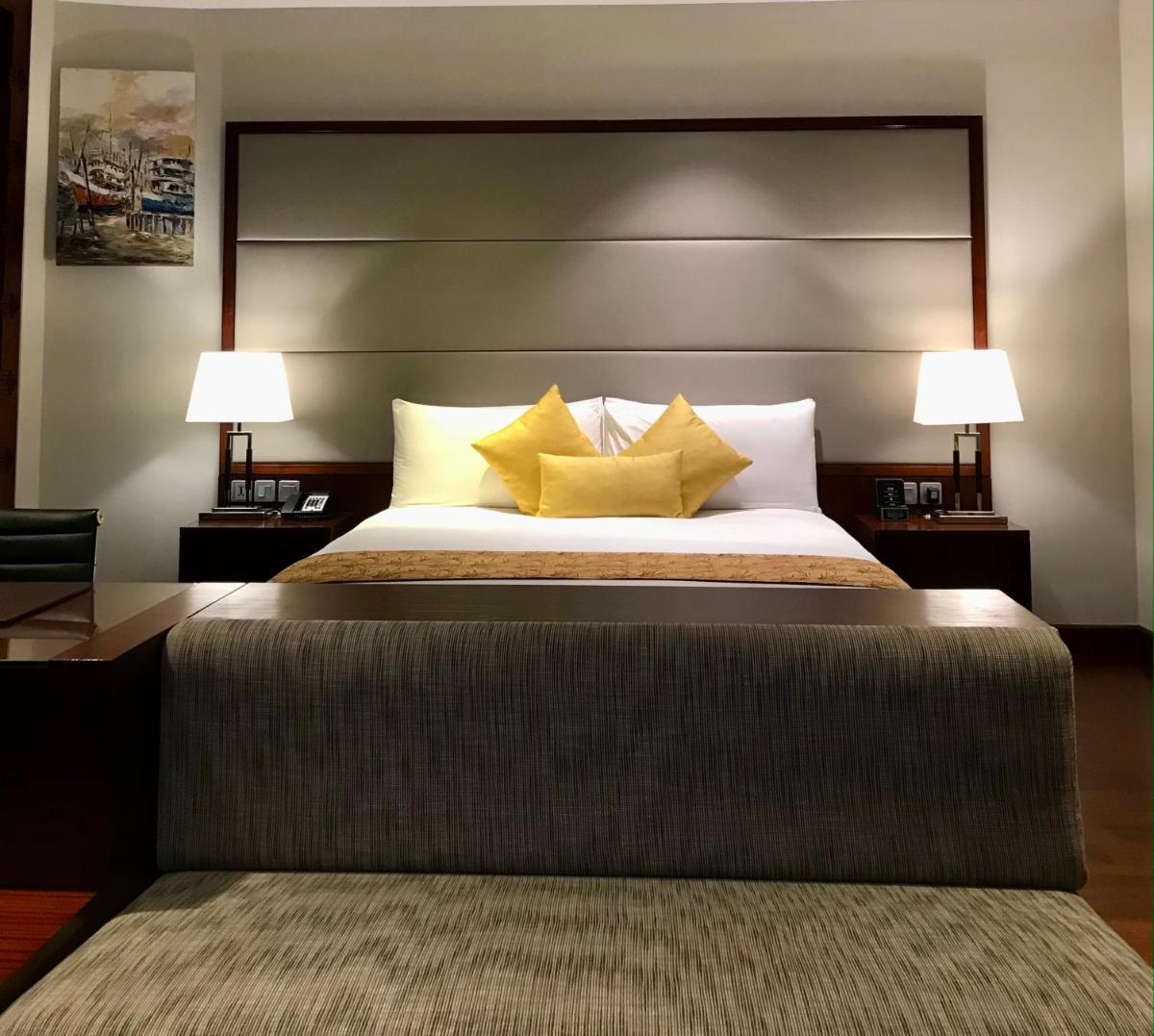a bedroom with a large bed with two lamps at Crowne Plaza Kochi by IHG in Cochin
