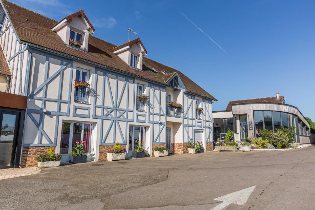 un grand bâtiment blanc et bleu avec des plantes en pot dans l'établissement Logis Hôtel Restaurant Aux Maisons, à Maisons-lès-Chaource