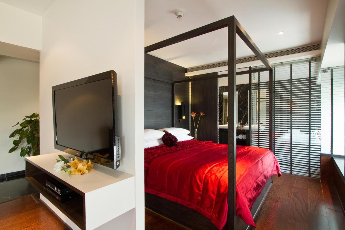 a bedroom with a red bed and a large screen tv at Svenska Design Hotel in Mumbai