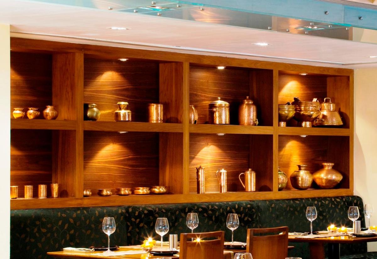 a restaurant with wooden shelves with wine glasses on tables at Blue Diamond Pune IHCL SeleQtions in Pune