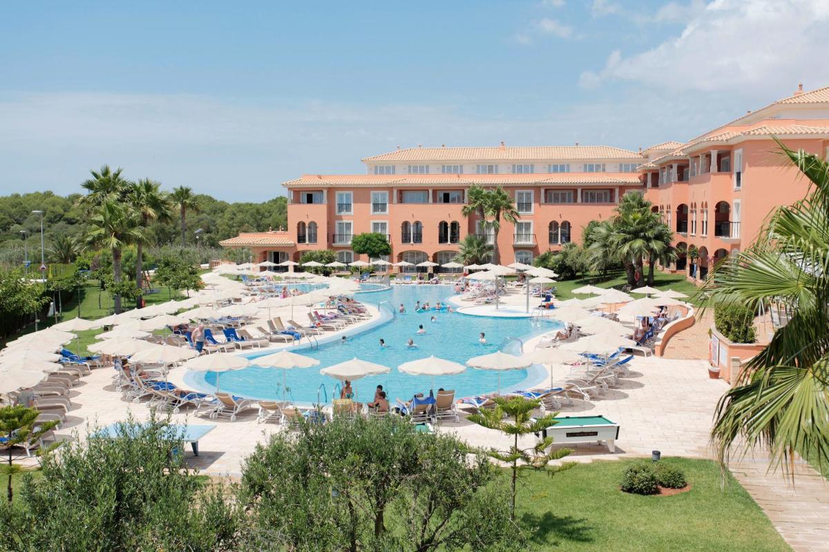 un complejo con una gran piscina con gente dentro en Grupotel Macarella Suites & Spa, en Son Xoriguer
