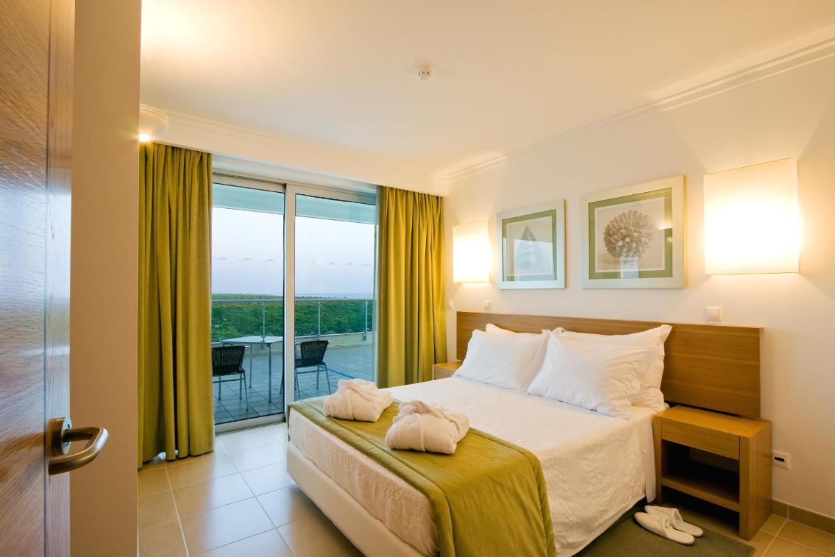 um quarto de hotel com uma cama e uma varanda em Monte Gordo Hotel Apartamentos & Spa em Monte Gordo