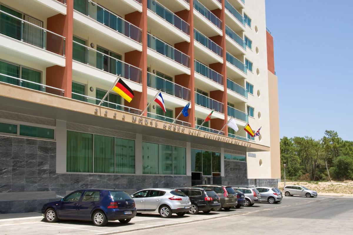 uma fileira de carros estacionados em frente a um prédio em Monte Gordo Hotel Apartamentos & Spa em Monte Gordo